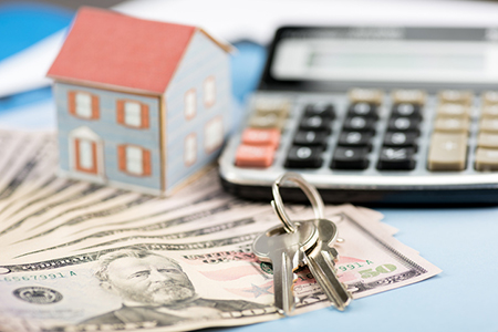 Calculator, cash and house keys, symbolizing the process of calculating how much house you can afford